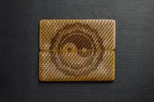 Yin Yang symbol etched on a wooden bed of nails with a dark textured background.